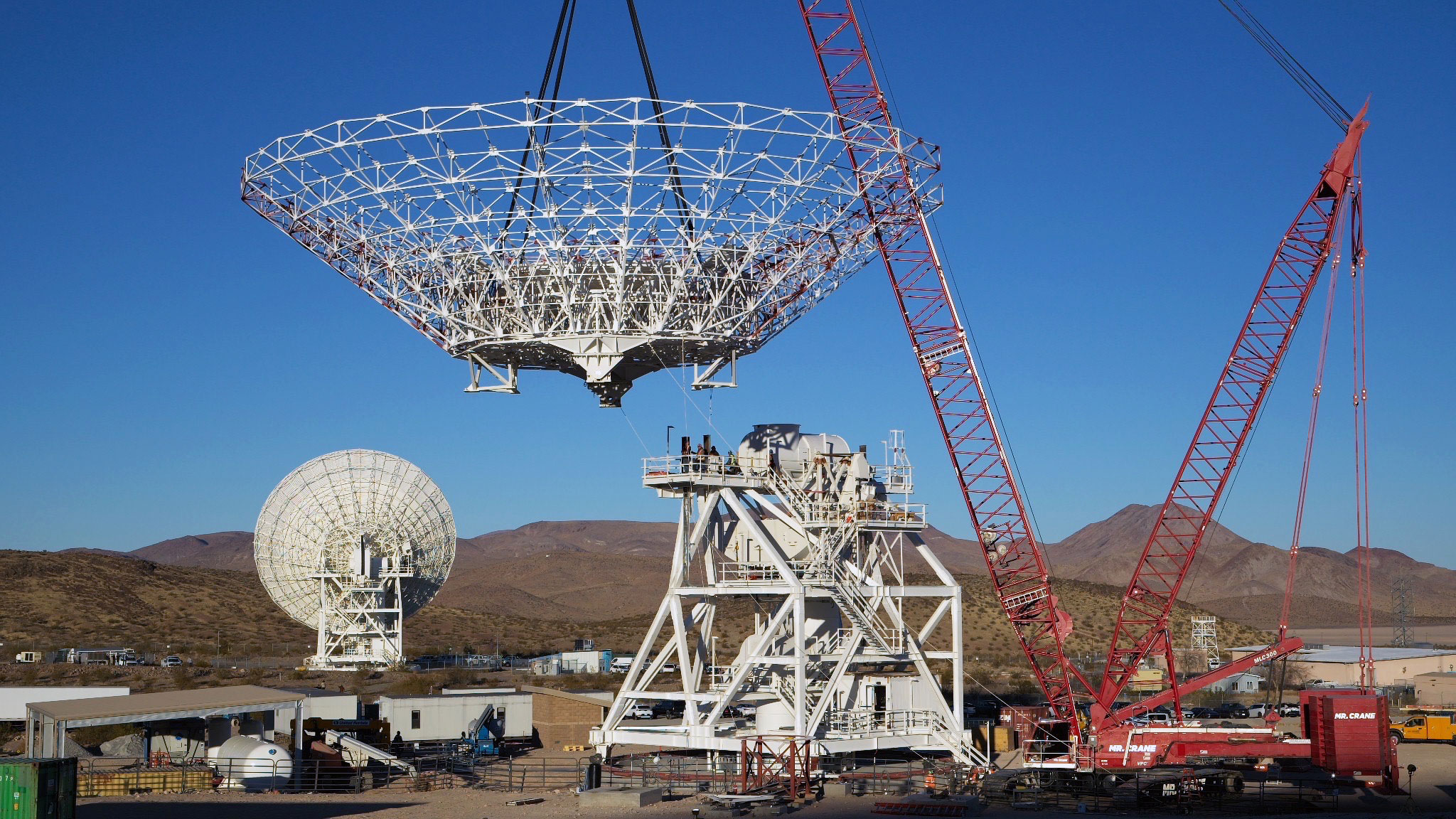 A crane lowers the steel reflector framework for Deep Space Station 23 into position