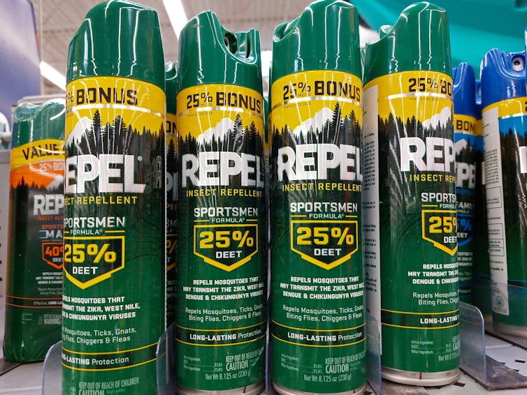 Cans of mosquito repellent on a supermarket shelf.