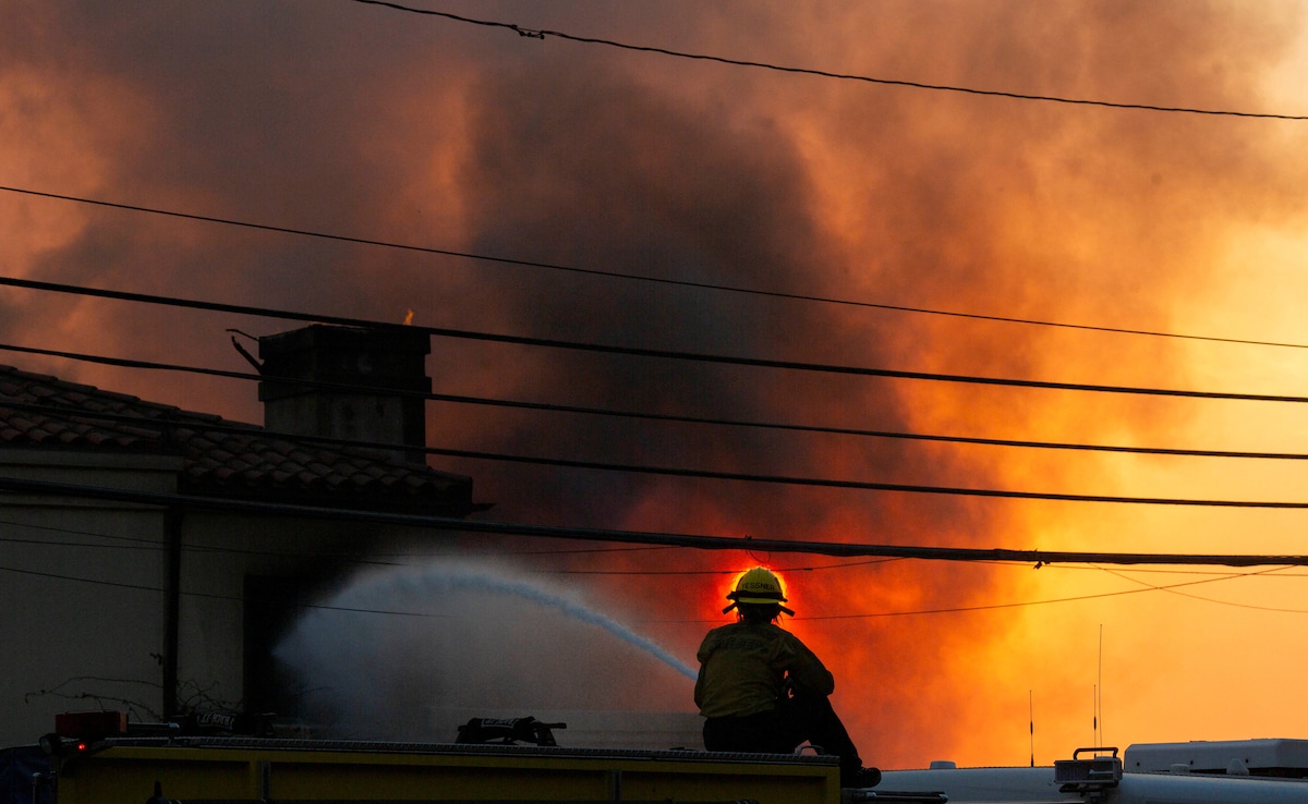 Firefighter battles the fire as it burns during a windstorm. Firefighter battles the fire as it burns during a windstorm.