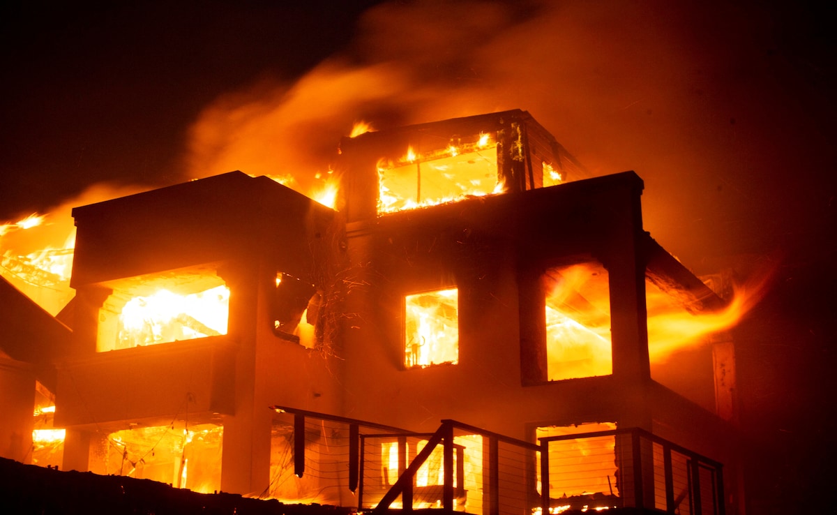 Flames rise from a structure as the Palisades fire burns during a windstorm. Flames rise from a structure as the Palisades fire burns during a windstorm.