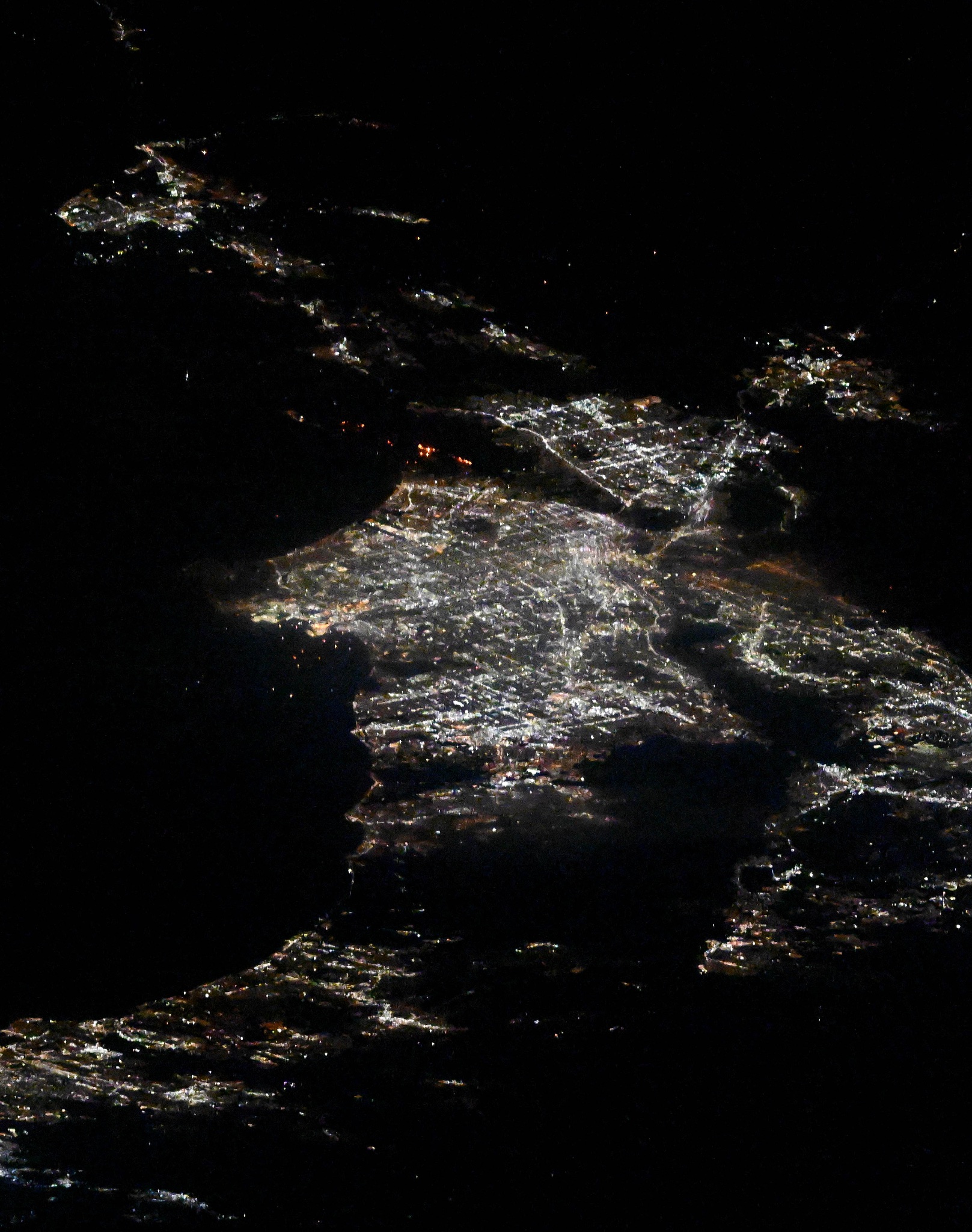 A view of Los Angeles, California from the International Space Station. The fires appear as orange lights just above center, in between two areas brightly lit by city lights.