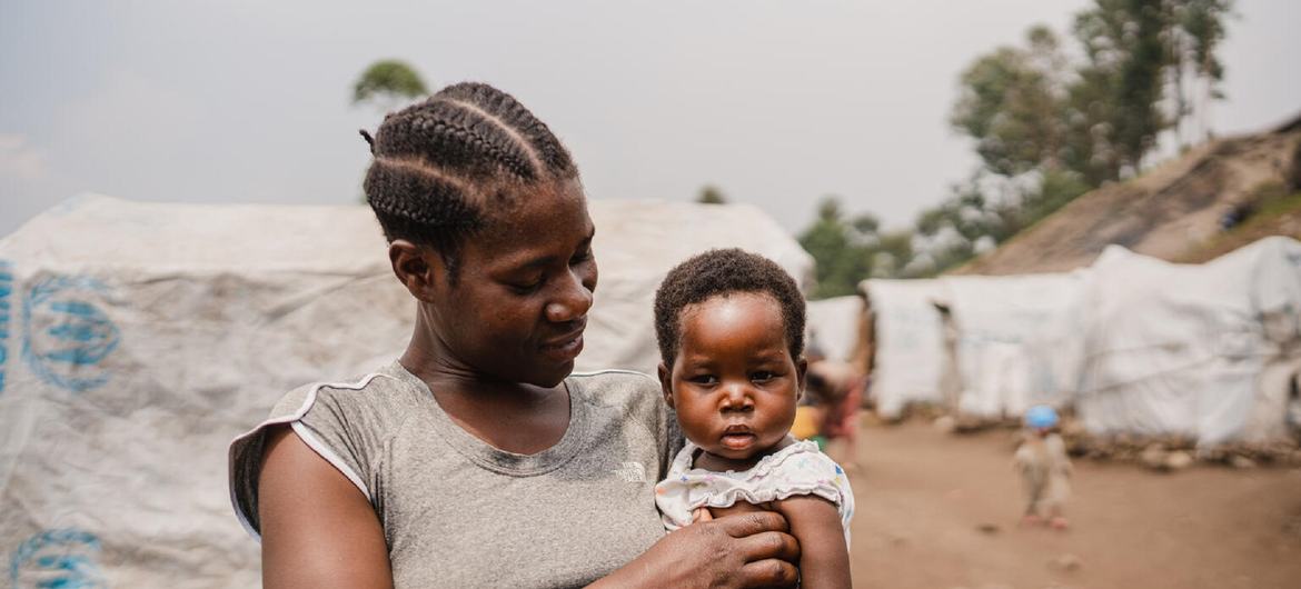 A mother holds her young child after having visited a UN-supported medical clinic at an IDP camp in North Kivu. A mother holds her young child after having visited a UN-supported medical clinic at an IDP camp in North Kivu.