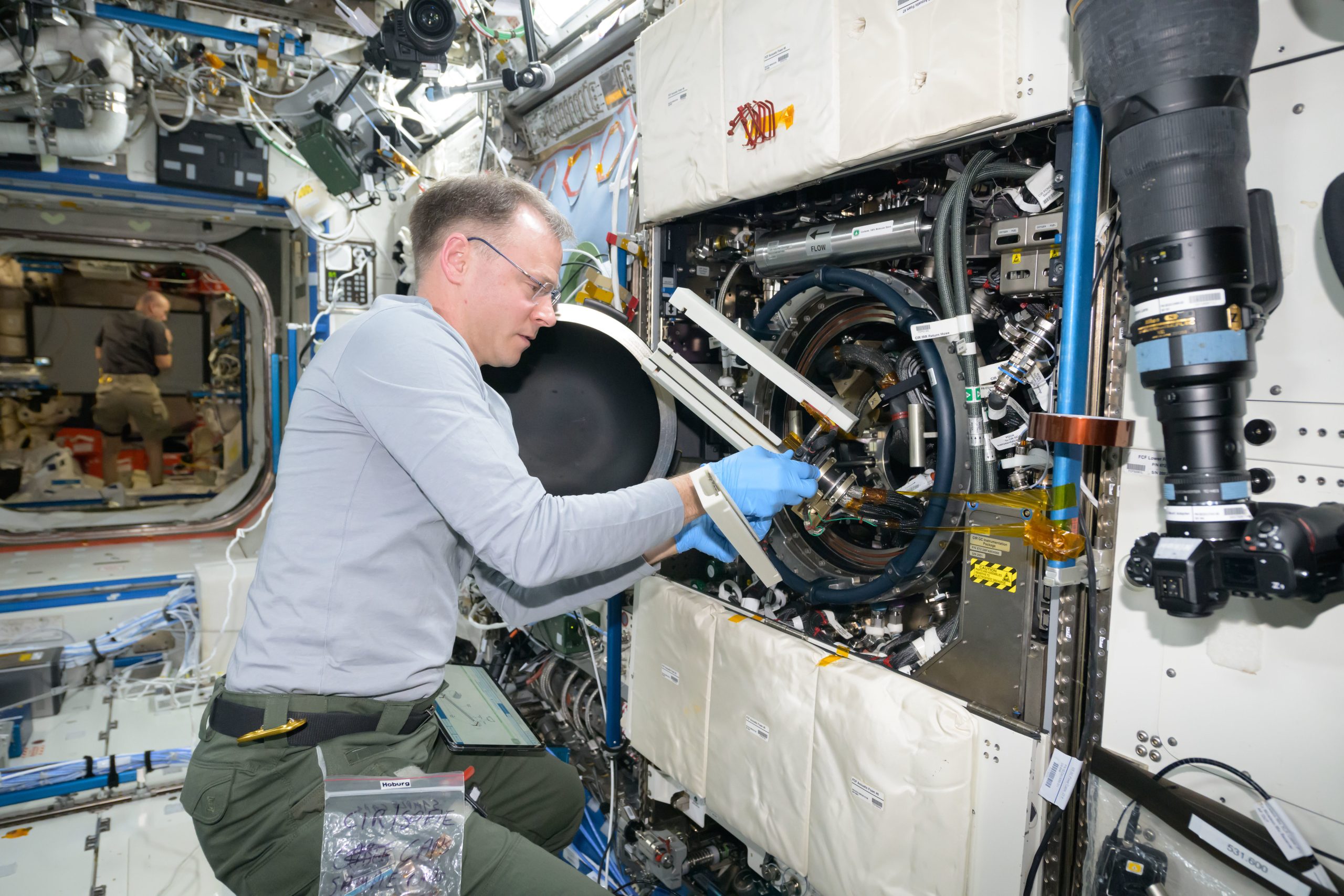 Astronaut Nick Hague swaps samples of materials to observe how they burn in weightlessness.