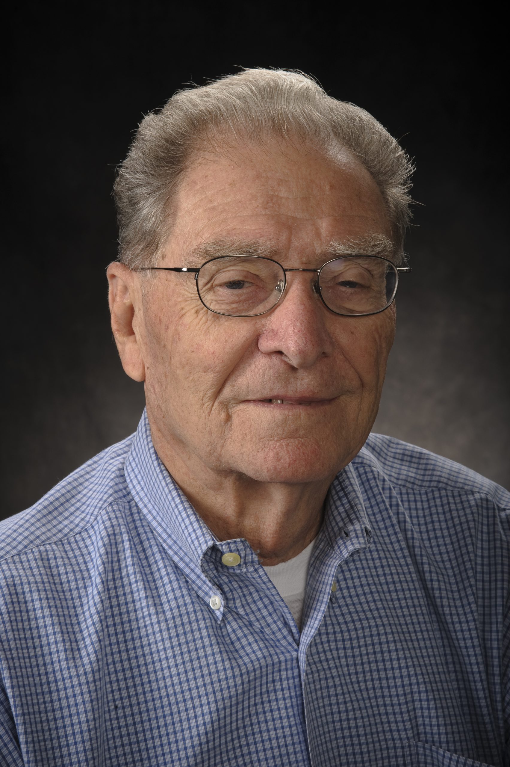 Portrait of John Boyd, known to many as Jack, in a blue shirt with a black background