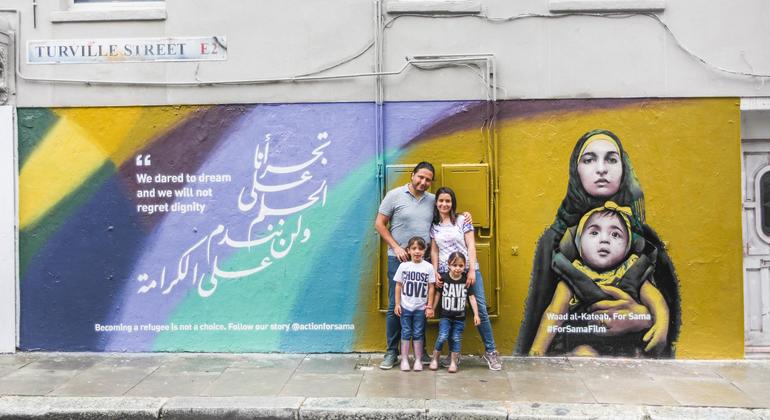 Waad Al-Kateab stands with her family in front of a mural for her film, For Sama. Waad Al-Kateab stands with her family in front of a mural for her film, For Sama.