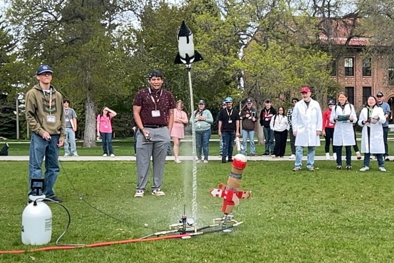 A water bottle rocket takes off in front of a crowd.