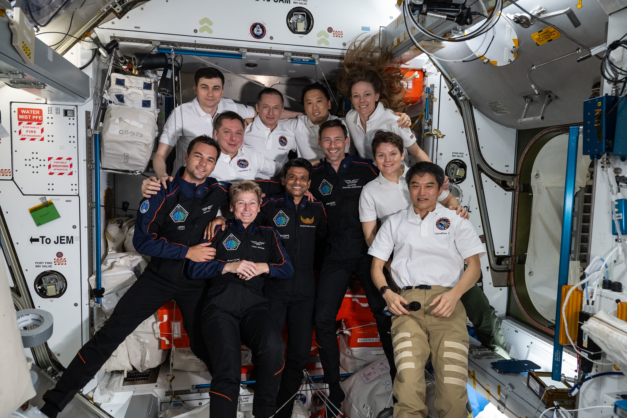 The Axiom Mission 4 and Expedition 73 crews, join together and smile for a group portrait inside the International Space Station's Harmony module. In the front row (from left) are Ax-4 crewmates Tibor Kapu, Peggy Whitson, Shubhanshu Shukla, and Sławosz Uznański-Wiśniewski with Expedition 73 crewmates Anne McClain and Takuya Onishi. In the rear are, Expedition 73 crewmates Alexey Zubritskiy, Kirill Peskov, Sergey Ryzhikov, Jonny Kim, and Nichole Ayers.