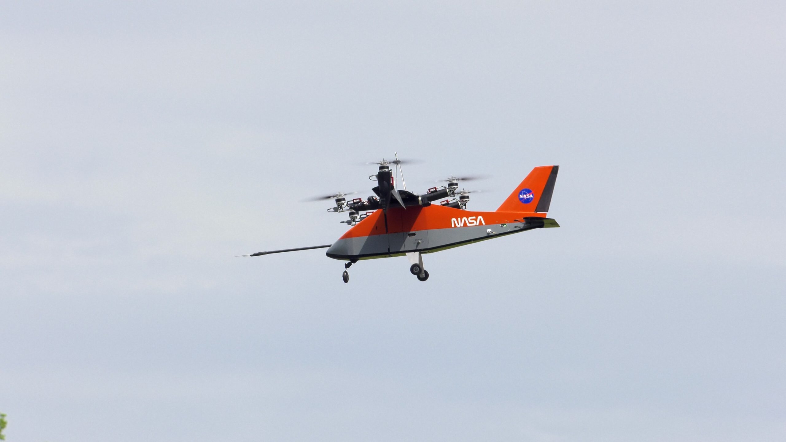An orange-colored small aircraft flies as it tests air taxi technologies.