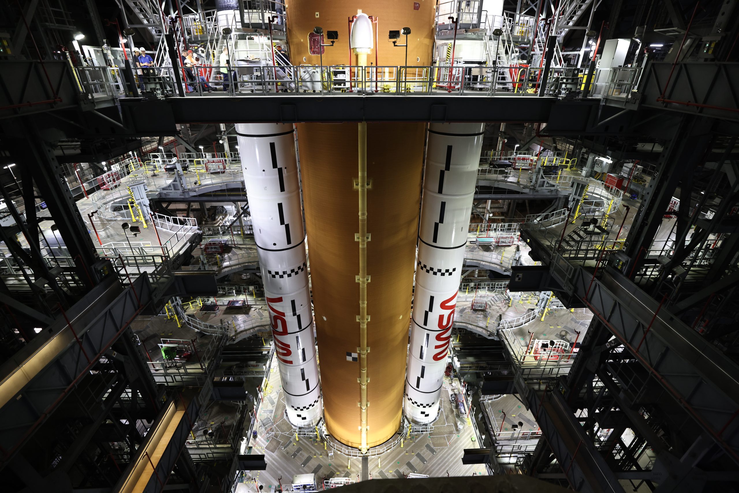 Image shows orange rocket stage with two large solid rocket boosters stacked alongside on March 23.