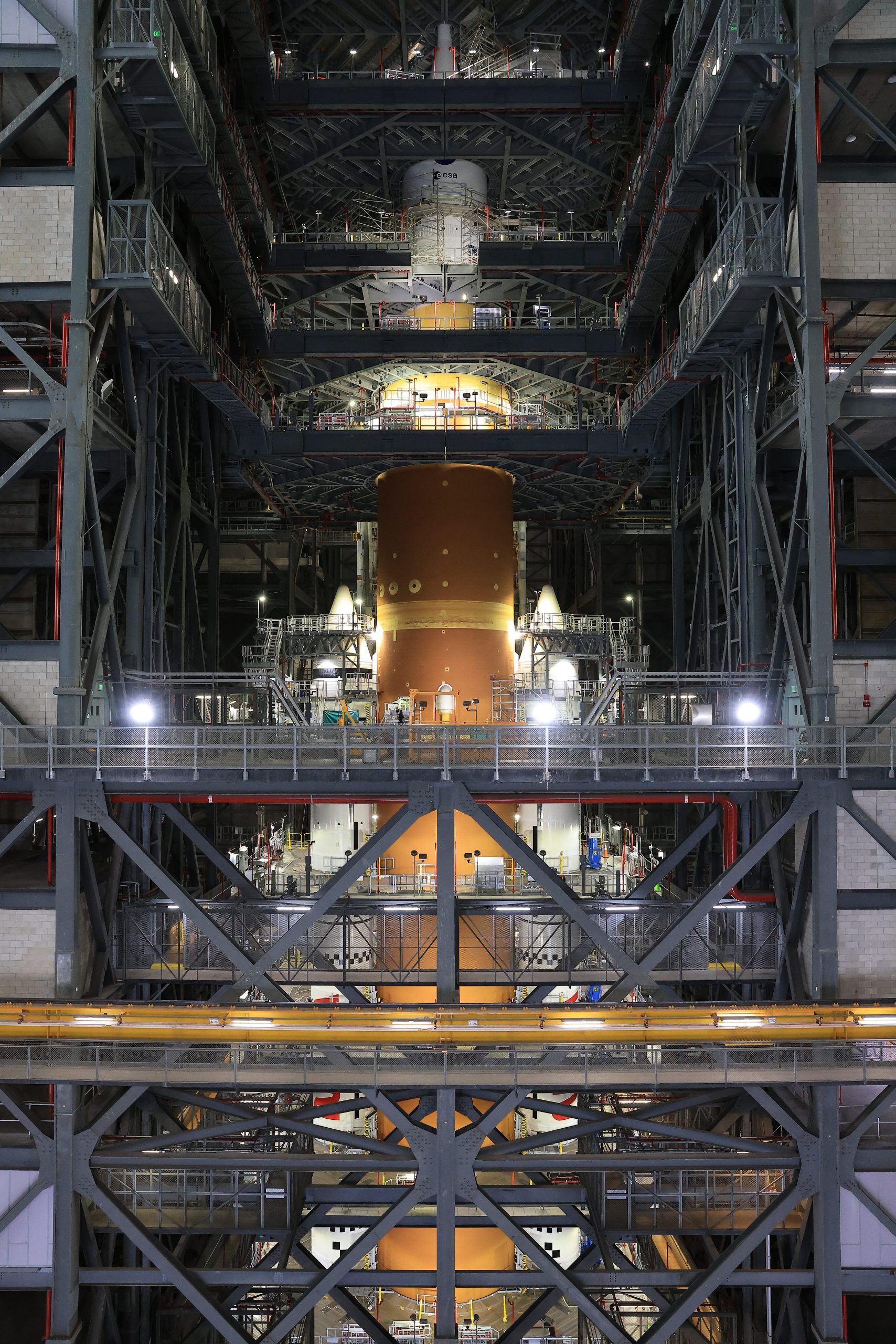 The orange core stage of the Artemis II rocket with white boosters on each side fully stacked inside the Vehicle Assembly Building at NASA's Kennedy Space Center in Florida on Saturday, Oct. 18, 2025.