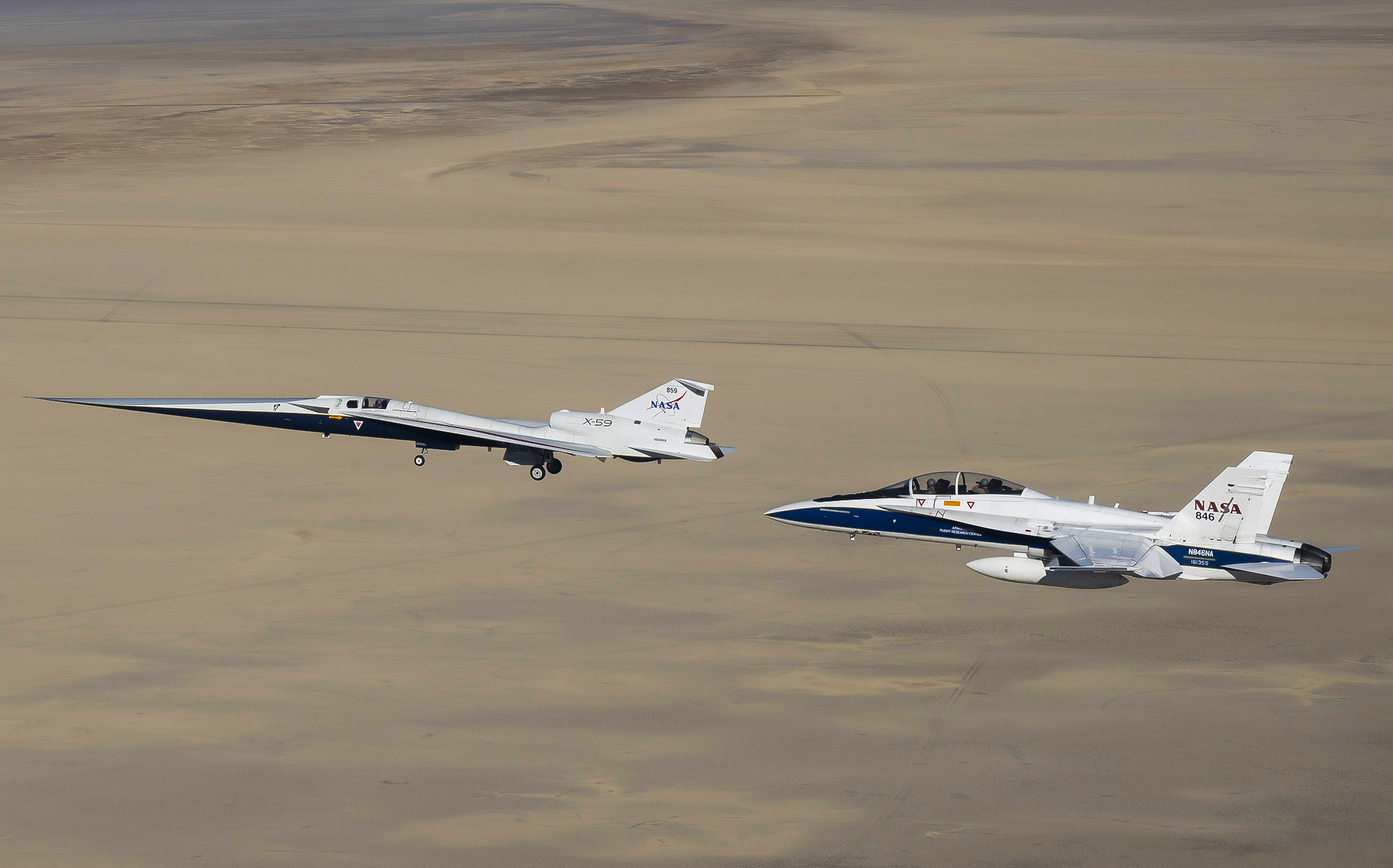 NASA’s X-59 flies above the Mojave Desert with a NASA F-15 chase aircraft nearby.