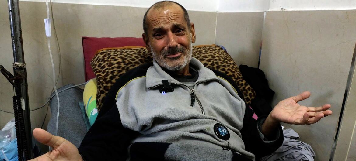 Mundhir Abu Foul, a cancer patient in Gaza, sits on a hospital bed with his hands open, appearing to speak or gesture.