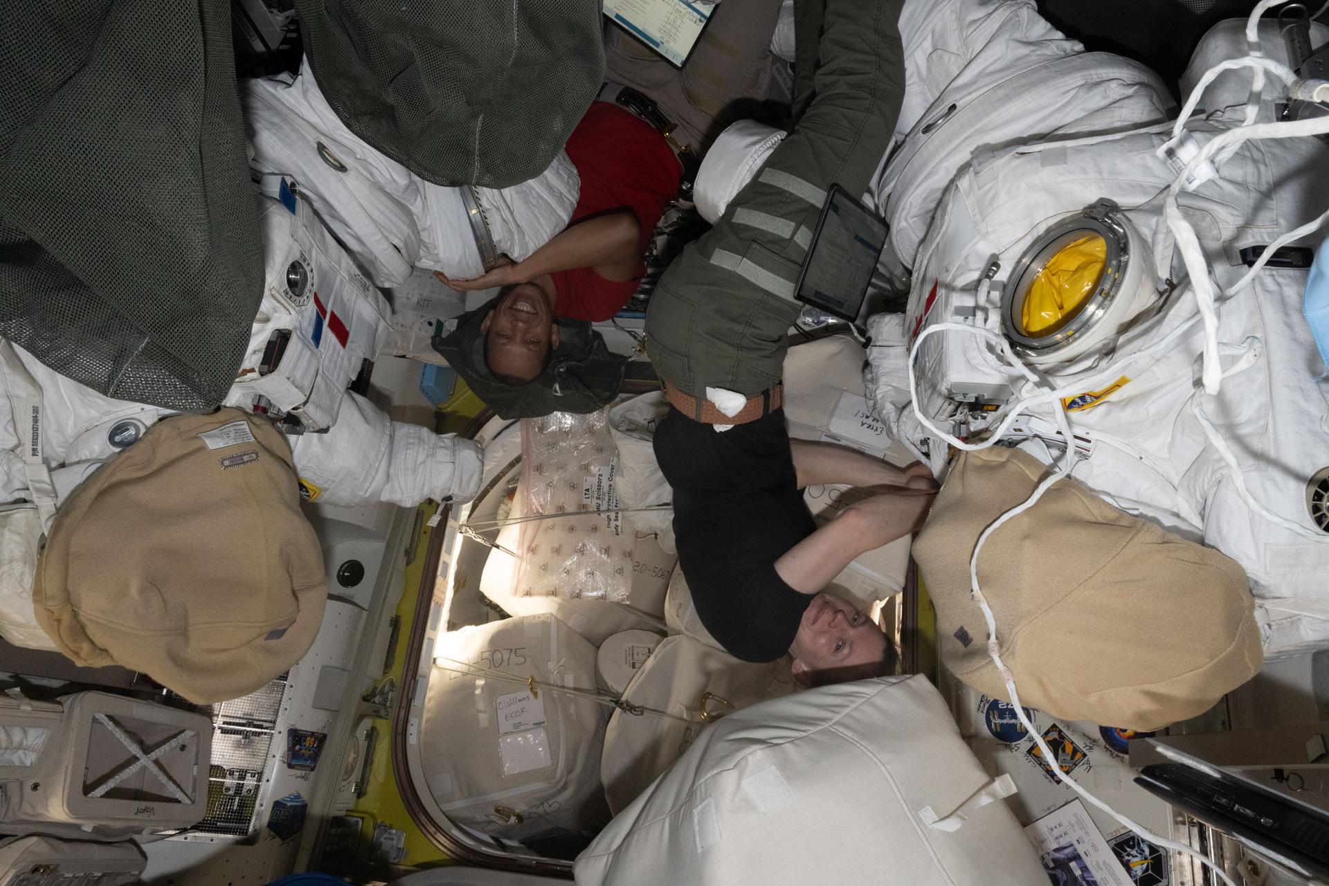 NASA astronauts Chris Williams and Zena Cardman, both Expedition 74 Flight Engineers, work on spacesuit maintenance inside the International Space Station's Quest airlock.